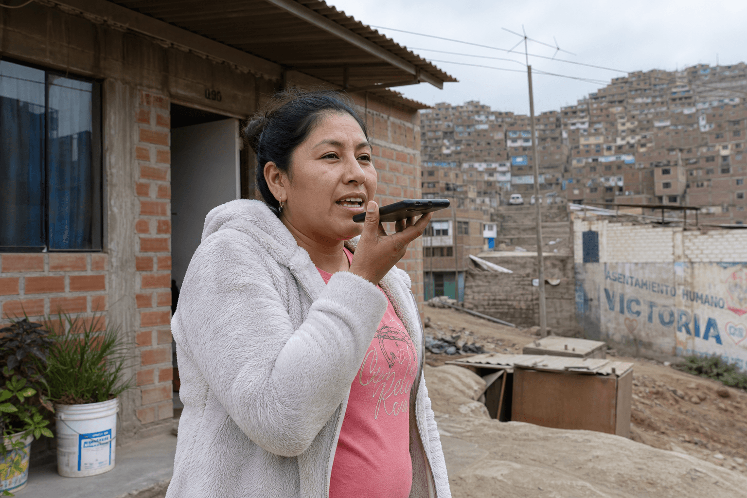 Una mujer envía un audio frente a su vivienda